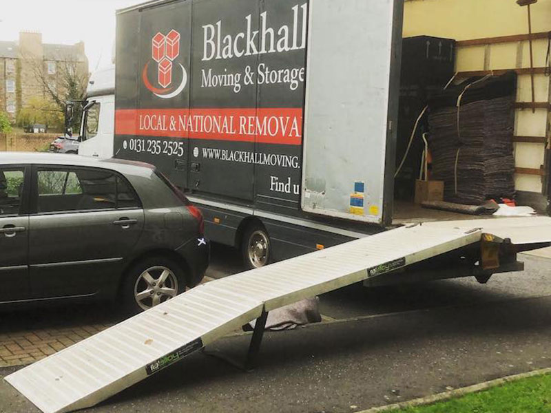 removal van with ramp coming from it, next to parked car