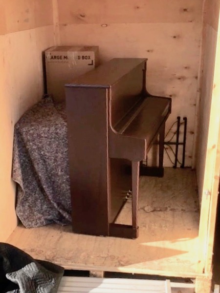 upright piano stored in the middle of storage container